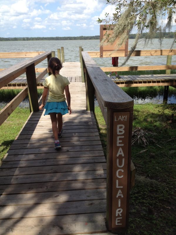 Little girl walking on a dock towards the water