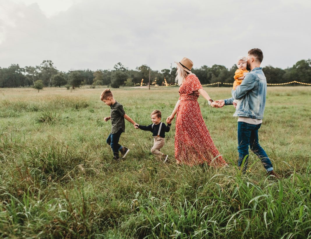 family of five walking in a grass field