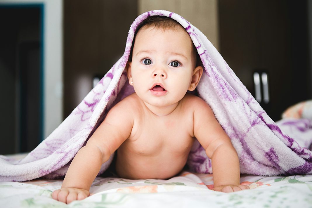 jonathan-borba via unsplash baby girl pushing self up on arms with purple blanket over head