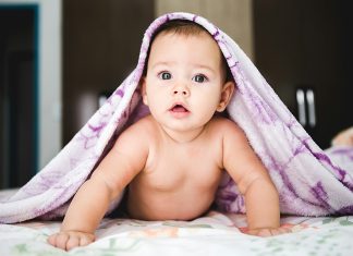 Writing A Birth Plan That Will Stick jonathan-borba via unsplash baby girl pushing self up on arms with purple blanket over head