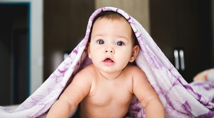Writing A Birth Plan That Will Stick jonathan-borba via unsplash baby girl pushing self up on arms with purple blanket over head
