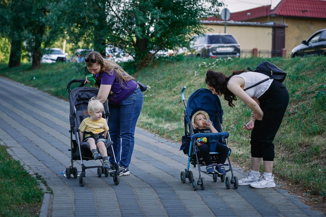 maxim-tolchinskiy via unsplash two moms leaning over their strollers on a walk