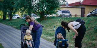 Stroller date, anyone? Perfect Parks for Mom Meetups maxim-tolchinskiy via unsplash two moms leaning over their strollers on a walk