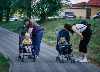 maxim-tolchinskiy via unsplash two moms leaning over their strollers on a walk