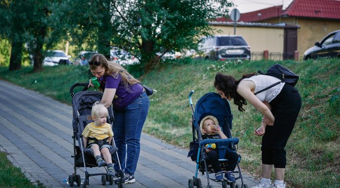 Stroller date, anyone? Perfect Parks for Mom Meetups maxim-tolchinskiy via unsplash two moms leaning over their strollers on a walk