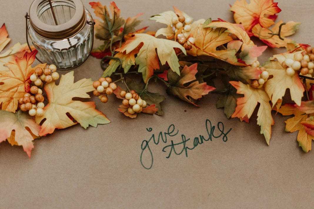 thanksgiving recipes priscilla-du-preez via unsplash candle and leaves on brown paper with words 'give thanks' in marker written on the paper