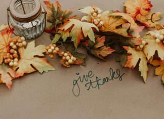 priscilla-du-preez via unsplash candle and leaves on brown paper with words 'give thanks' in marker written on the paper