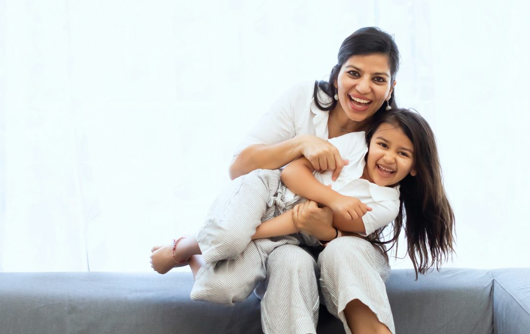 vivek-kumar via unsplash a woman and child sitting on a couch laughing at the camera