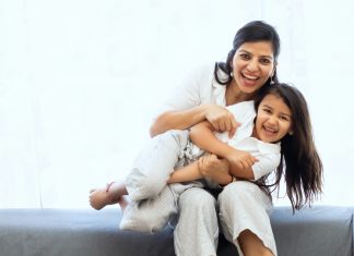 vivek-kumar via unsplash a woman and child sitting on a couch laughing at the camera