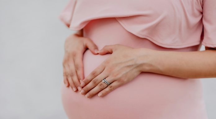 Pregnant Foodie Mom Plans Ahead! juan-encalada via unsplash pregnant belly in a pink dress with hands on the bump and wedding rings