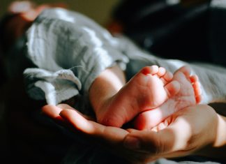 omar-lopez via unsplash two baby feet in an adult hand