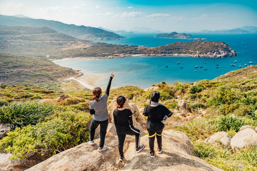 Tron Le via Unsplash three women on a rock overlooking forrest and the ocean