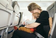 Paul Hanaoka via Unsplash - mom and baby in an airplane seat together looking at something in mom's lap.