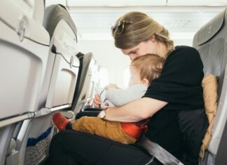 Paul Hanaoka via Unsplash - mom and baby in an airplane seat together looking at something in mom's lap.