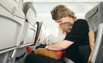Paul Hanaoka via Unsplash - mom and baby in an airplane seat together looking at something in mom's lap.