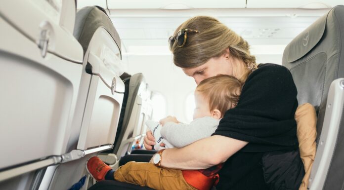 Toddler Travel Kit: Tips, Tricks, and a DIY Paul Hanaoka via Unsplash - mom and baby in an airplane seat together looking at something in mom's lap.
