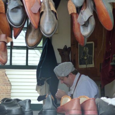 An authentic shoemaker works on his wares 