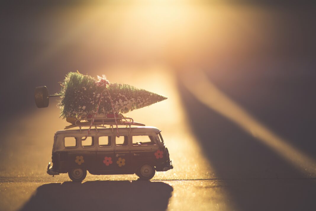 Denist Johnson via Unsplash toy van with little Christmas tree on top with the sun shining behind it