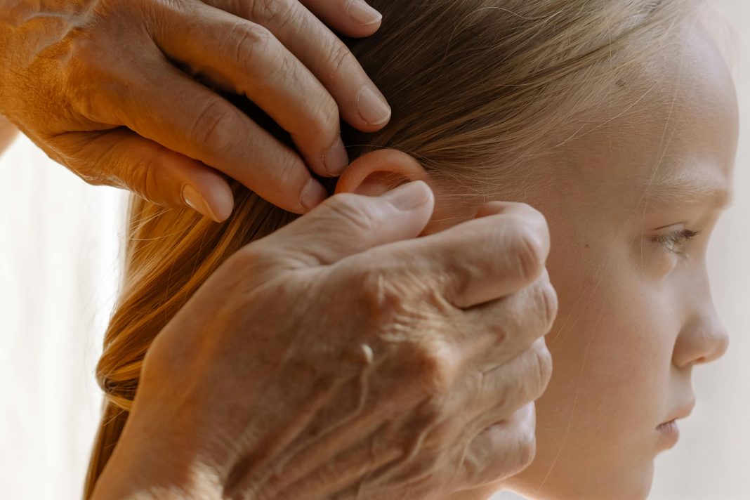 Grandmother gently combs a young girl’s hair in a sun-lit room, attentively inspecting each strand for lice