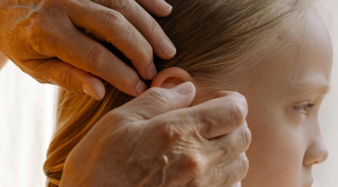 Grandmother gently combs a young girl’s hair in a sun-lit room, attentively inspecting each strand for lice