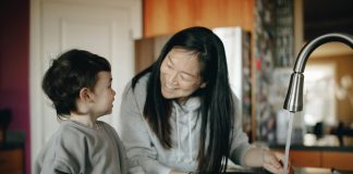 mother smiling at son washng berries for morning school routine