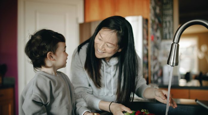 mother smiling at son washng berries for morning school routine