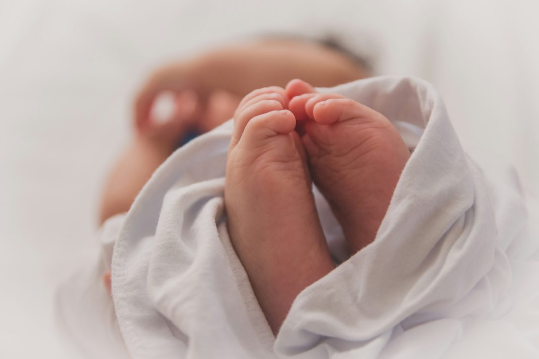 Luma Pimentel via Unsplash newborn baby feet wrapped in white blanket