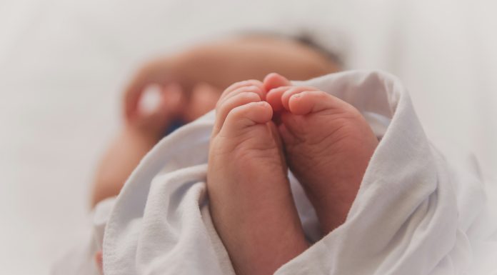 Luma Pimentel via Unsplash newborn baby feet wrapped in white blanket