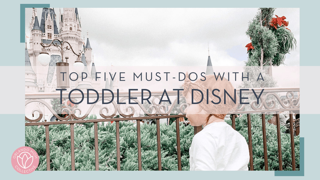 little girl in front of cinderella castle at the fence with 'top five must-dos with a toddler at disney' in font in front of image