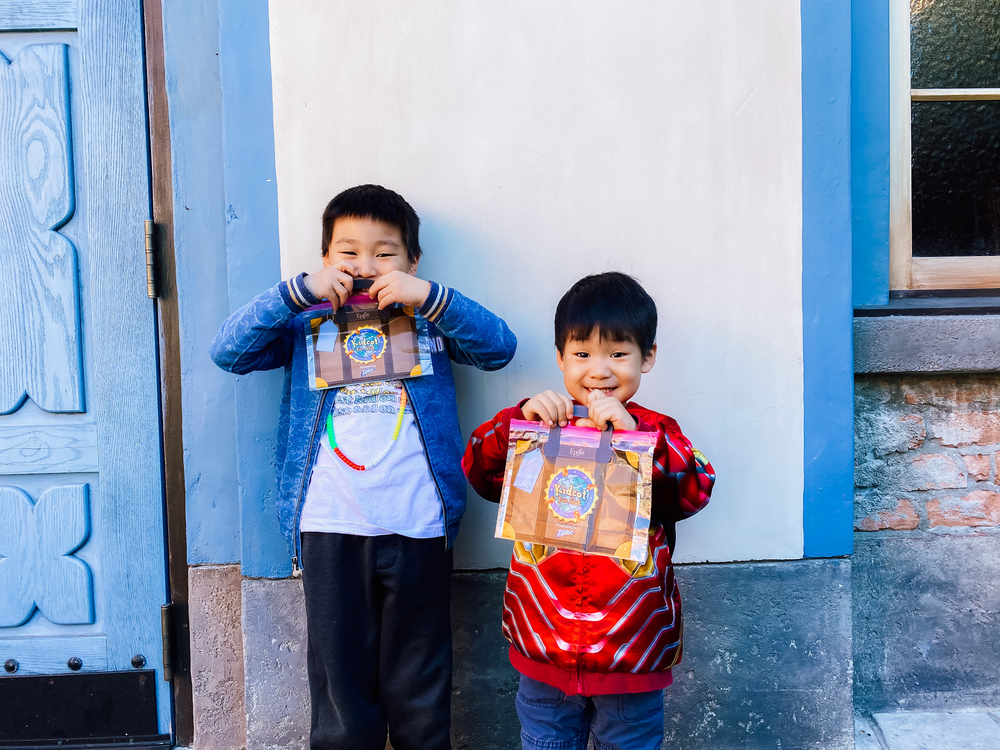 two kids with kid cot bags in front of their faces