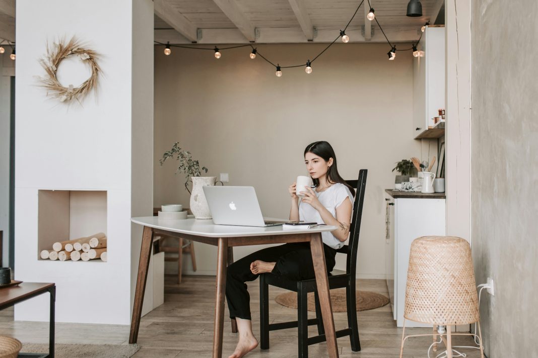 woman drinking coffee staring at her computer, presumably in the early morning. waking up before your kids