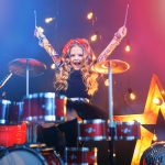 Beautiful girl playing the drums on a black background