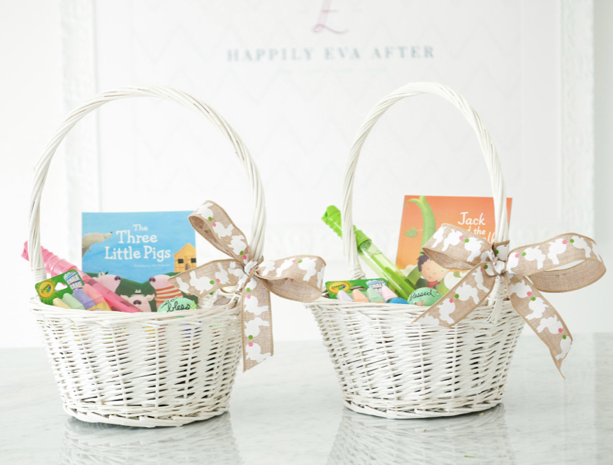 two white easter baskets with bunny ribbon tied on the side with toys and books coming out of the top