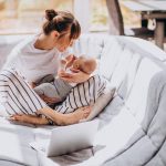 Young mother with her kid working at home on a computer