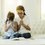 woman and little girl  praying on holy bible