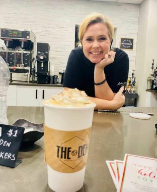 A delicious latte with whipped cream and a smiling mom behind it!