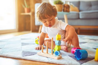 Beautiful toddler child girl playing with toys on the carpet