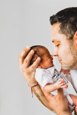 father nose to se and holding newborn in hands 