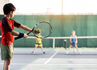 Cheerful kids playing tennis on court