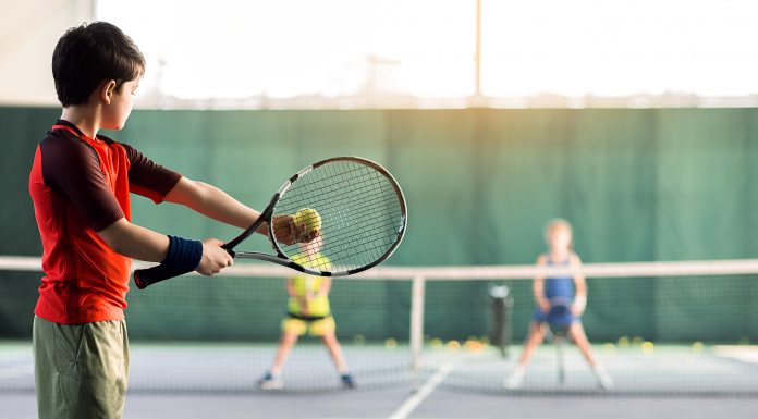 Cheerful kids playing tennis on court