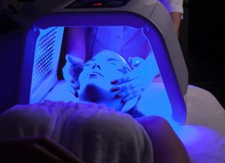 Young woman having LED light facial treatment in beauty salon