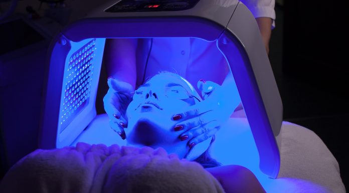 Young woman having LED light facial treatment in beauty salon