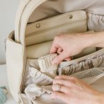 putting sock into beige diaper bag