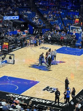 people huddled at half court of the Kia Center