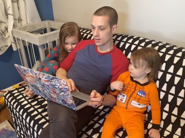 Dad and girls surveying makemomentos.com to find a book for him to read for them.