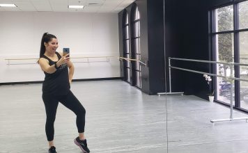 A latina mom is taking a mirror selfie at a dance studio