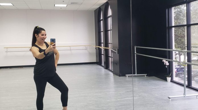 A latina mom is taking a mirror selfie at a dance studio