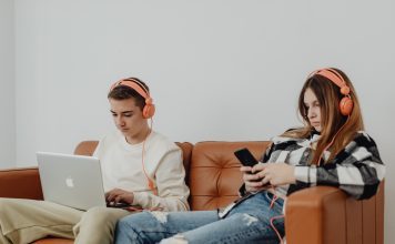 Internet Safety for Kids two teens with headphones on, one on the computer the other on their phone; internet safety