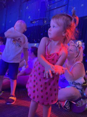 little girl dancing with Mickey at Disney Junior Play and Dance with boy behind her looking at ceiling