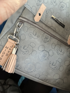 gray bag with beige accents with different faces of Mickey Mouse on it